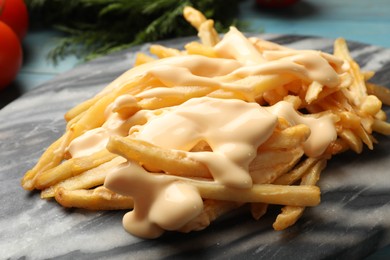 Photo of Delicious French fries with cheese sauce on table, closeup