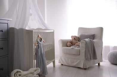 Photo of Baby room interior with comfortable crib and armchair