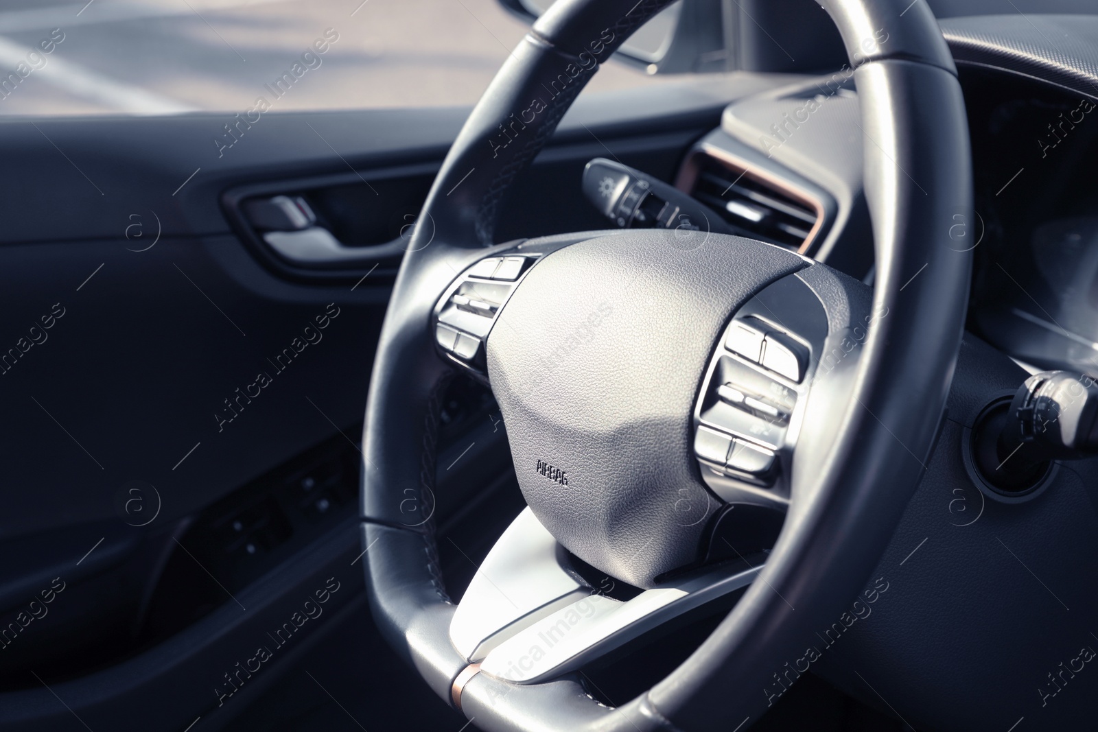 Photo of Black steering wheel inside of modern car, closeup. Space for text