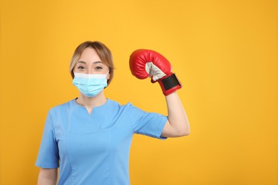 Photo of Doctor with protective mask and boxing gloves on yellow background, space for text. Strong immunity concept