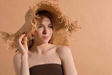 Photo of Beautiful young woman in straw hat on beige background, space for text