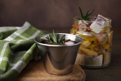 Tasty marinade with rosemary and fish on wooden table, closeup