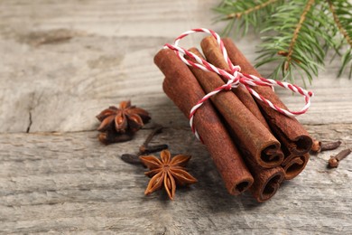Photo of Different spices. Aromatic cinnamon sticks, anise stars and clove seeds on wooden table, closeup. Space for text