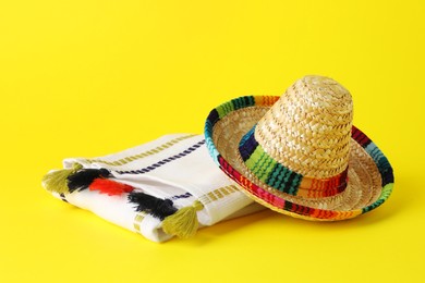 Mexican sombrero hat and poncho on yellow background