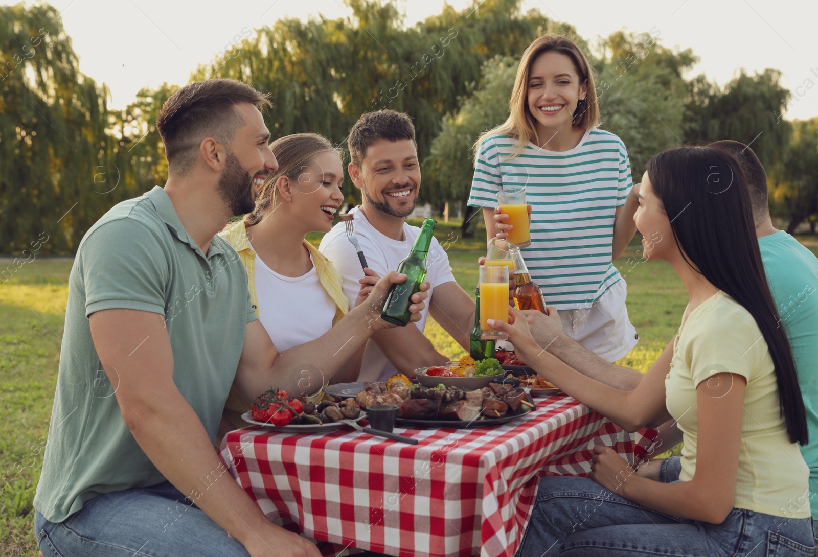 Photo of Happy friends with drinks and food at barbecue party in park