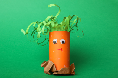 Toy carrot made of toilet paper hub on green background