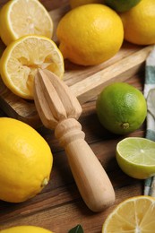 Photo of Squeezer with lemons on wooden table, closeup