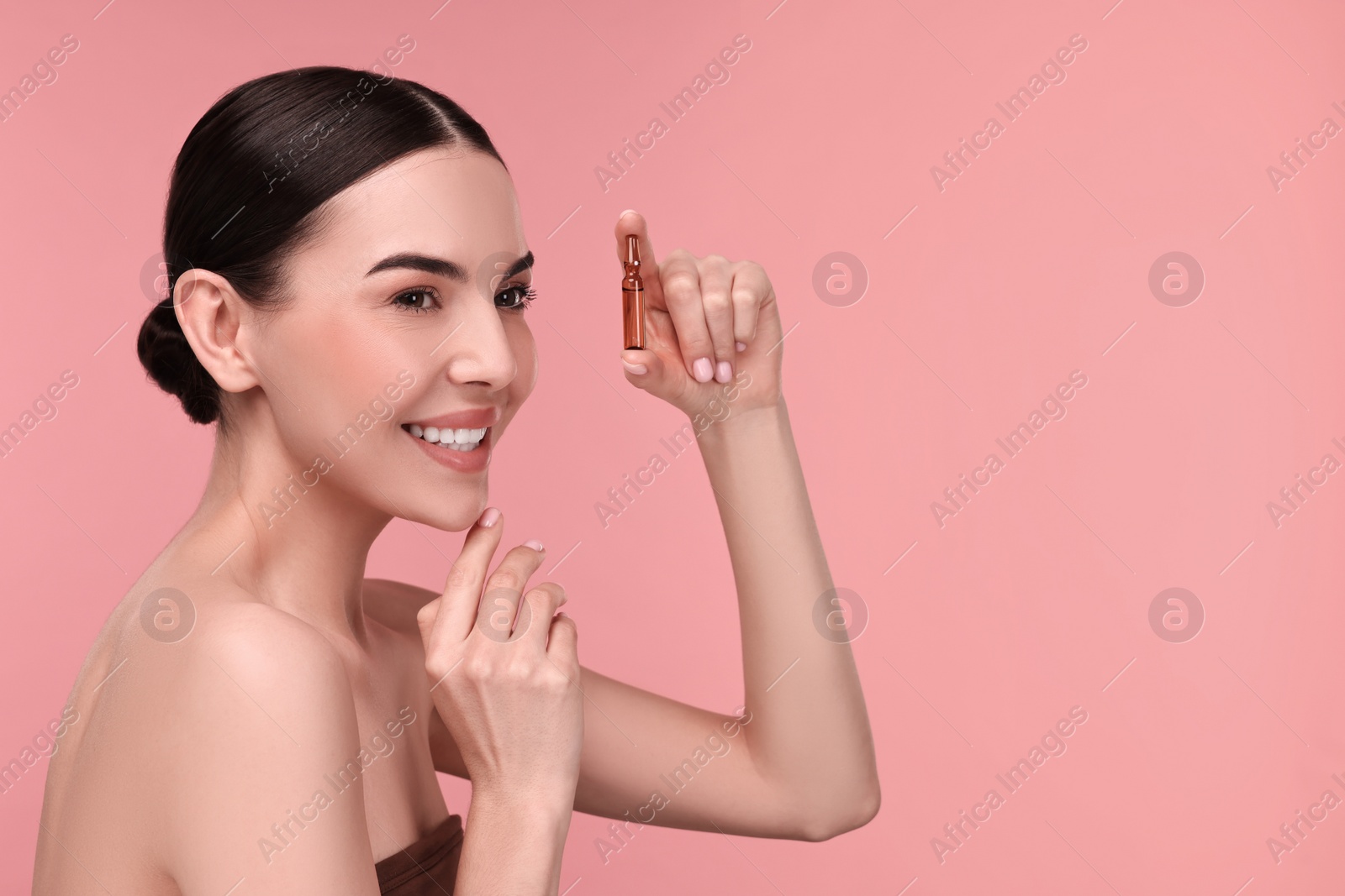 Photo of Beautiful young woman holding skincare ampoule on pink background. Space for text