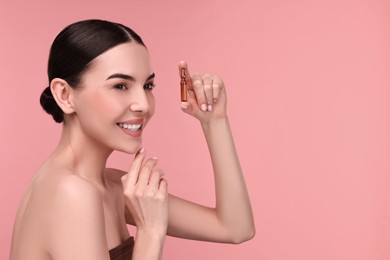 Photo of Beautiful young woman holding skincare ampoule on pink background. Space for text