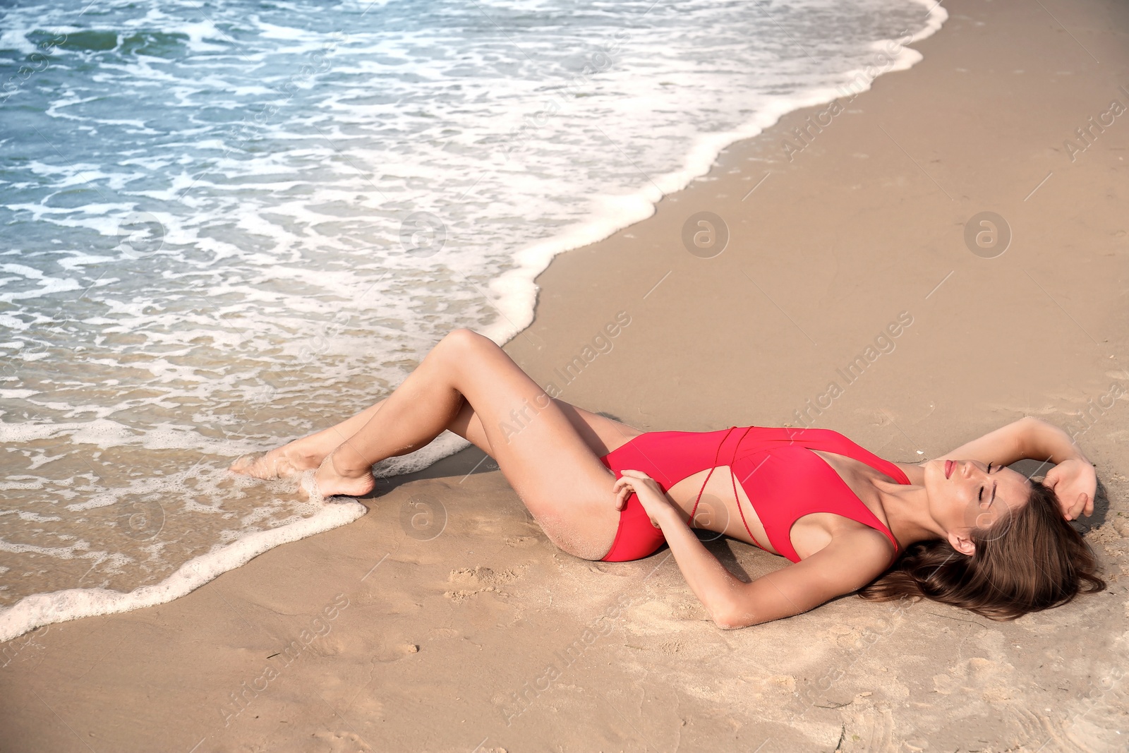 Photo of Attractive young woman in beautiful one-piece swimsuit on beach