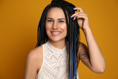 Photo of Beautiful young woman with nose piercing and dreadlocks on yellow background