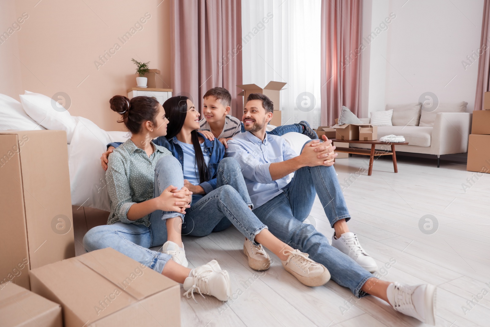 Photo of Happy family resting on floor near boxes in new apartment. Moving day