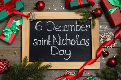 Photo of Blackboard with text 6 December Saint Nicholas Day, gift boxes and festive decor on wooden table, flat lay