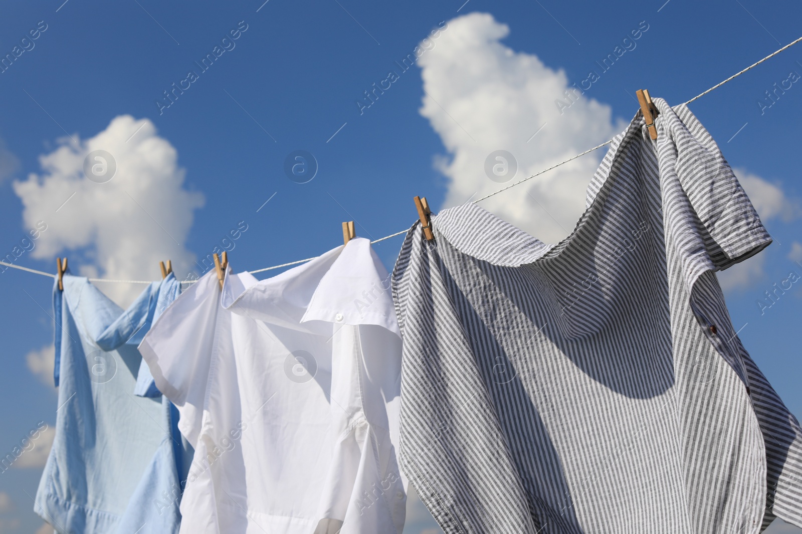 Photo of Clean clothes hanging on washing line against sky. Drying laundry