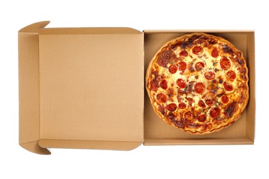 Photo of Delicious quiche with prosciutto and tomatoes in cardboard box isolated on white, top view. Food delivery