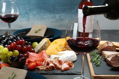 Pouring red wine into glass on served table at restaurant