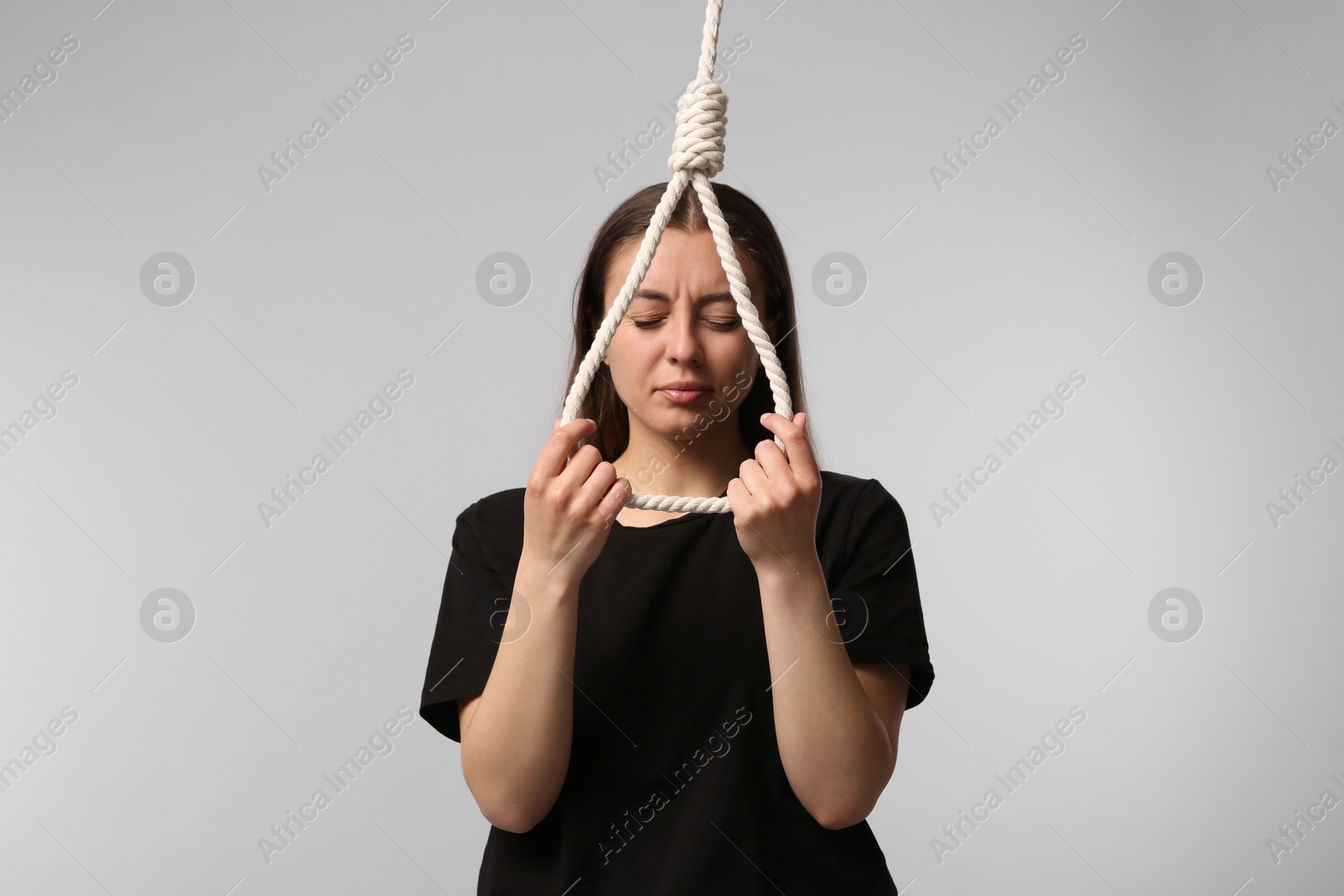 Photo of Depressed woman with rope noose on light grey background