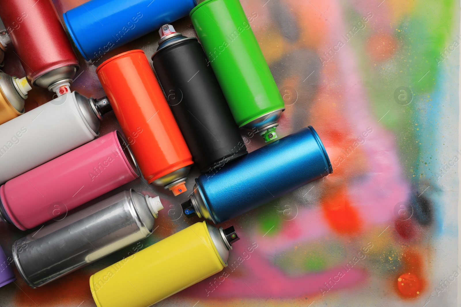 Photo of Cans of different graffiti spray paints on color background, flat lay