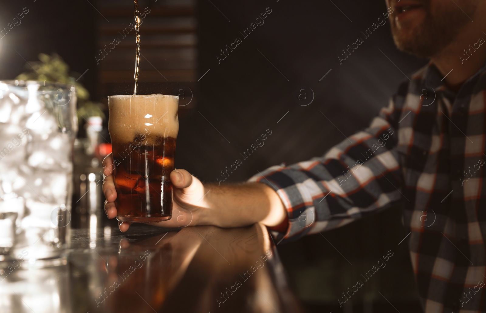 Photo of Man with glass of refreshing cola at bar counter, closeup. Pouring beverage