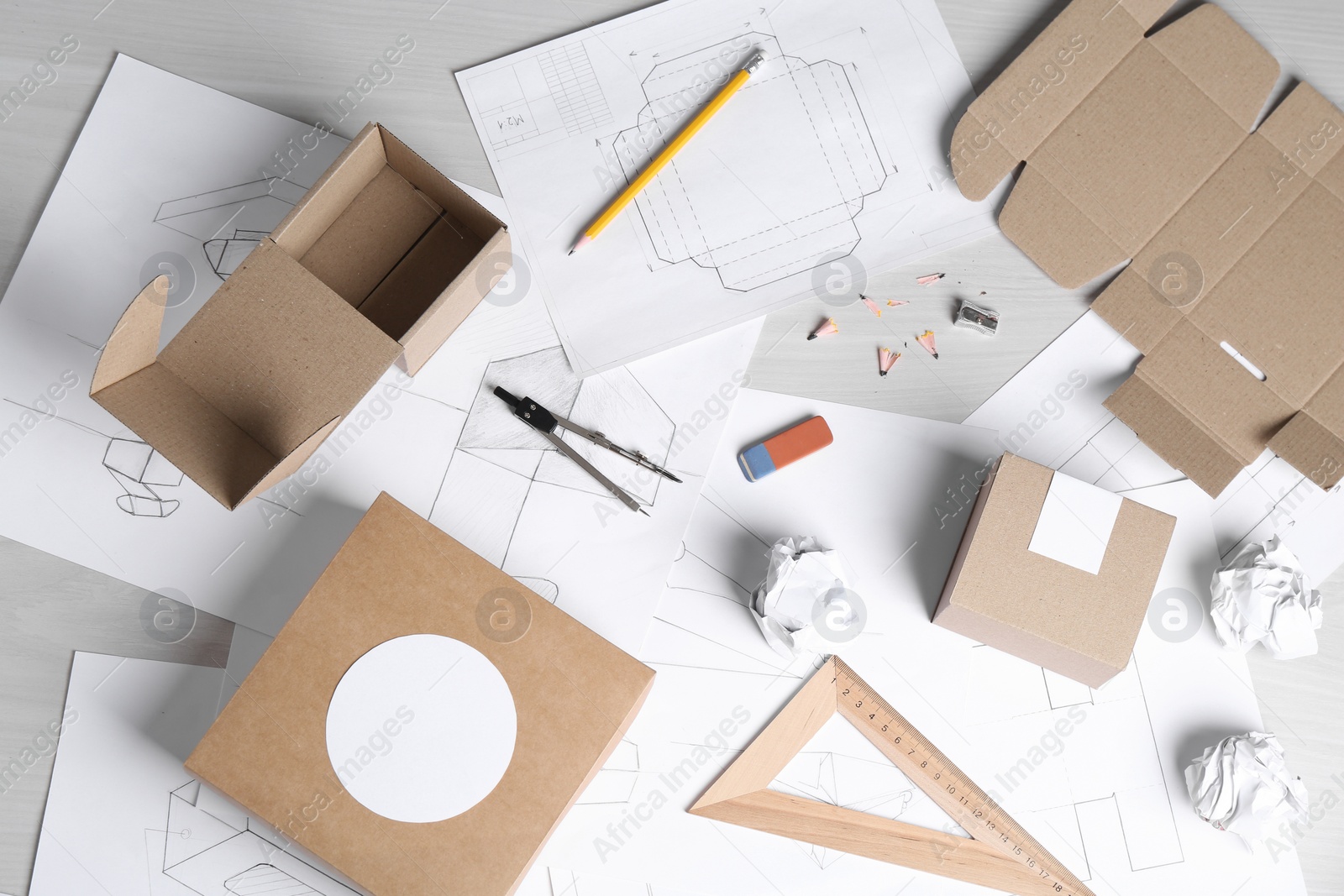 Photo of Creating packaging design. Drawings, boxes and stationery on light wooden table, flat lay