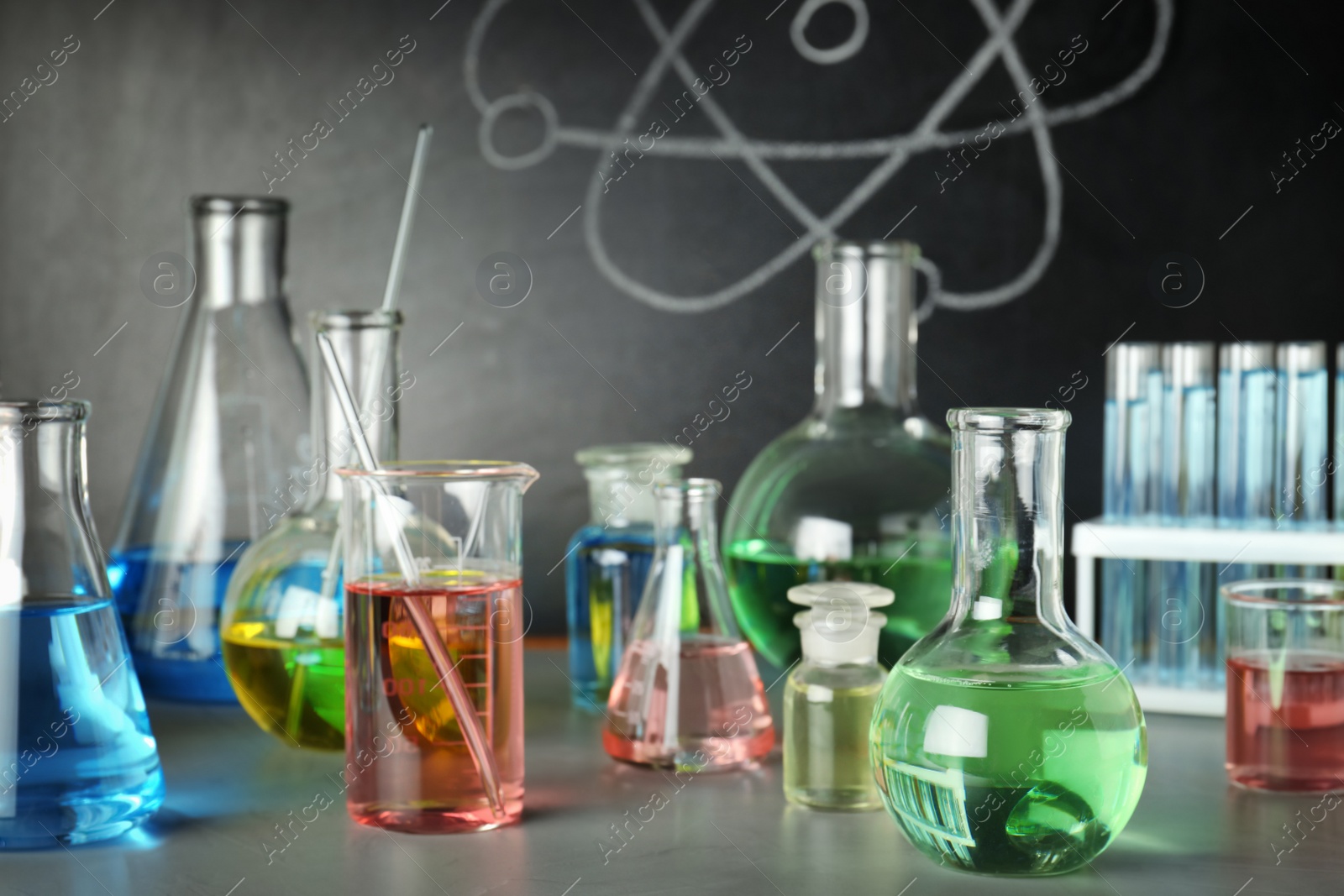 Photo of Laboratory glassware on table near chalkboard. Chemistry concept