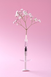 Cosmetology. Medical syringe and gypsophila on pink background