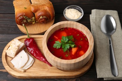 Photo of Delicious borsch served with pampushky and salo on wooden table. Traditional Ukrainian cuisine