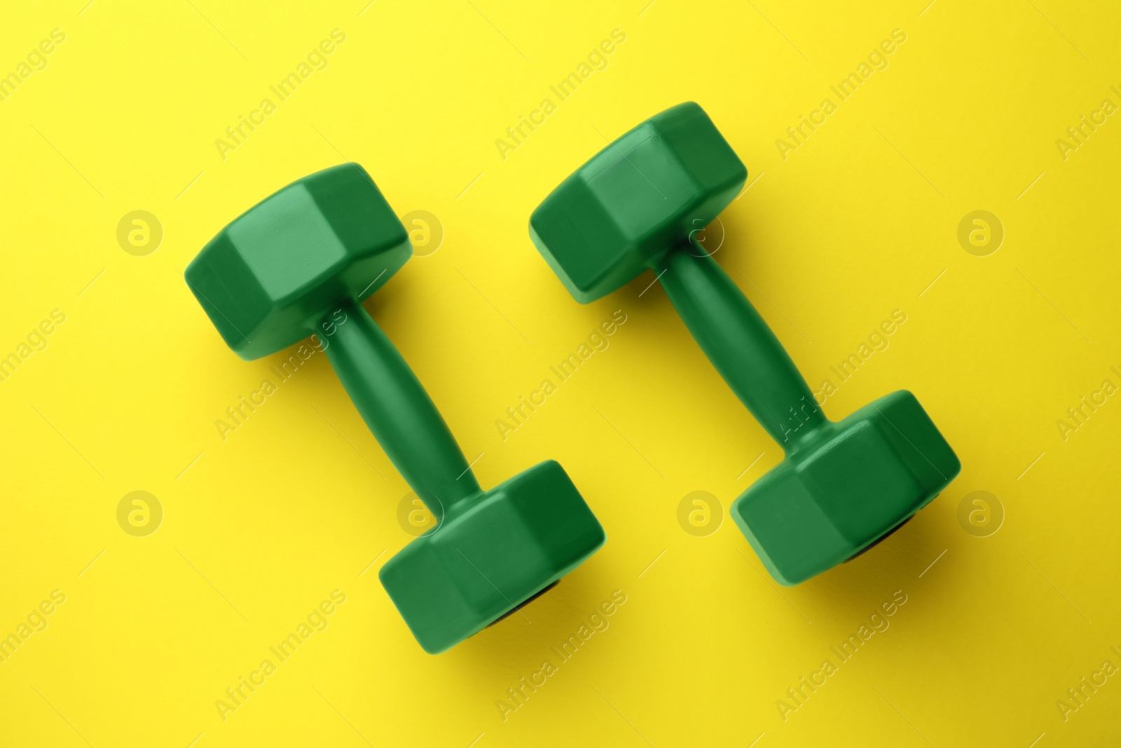 Photo of Stylish dumbbells on yellow background, flat lay