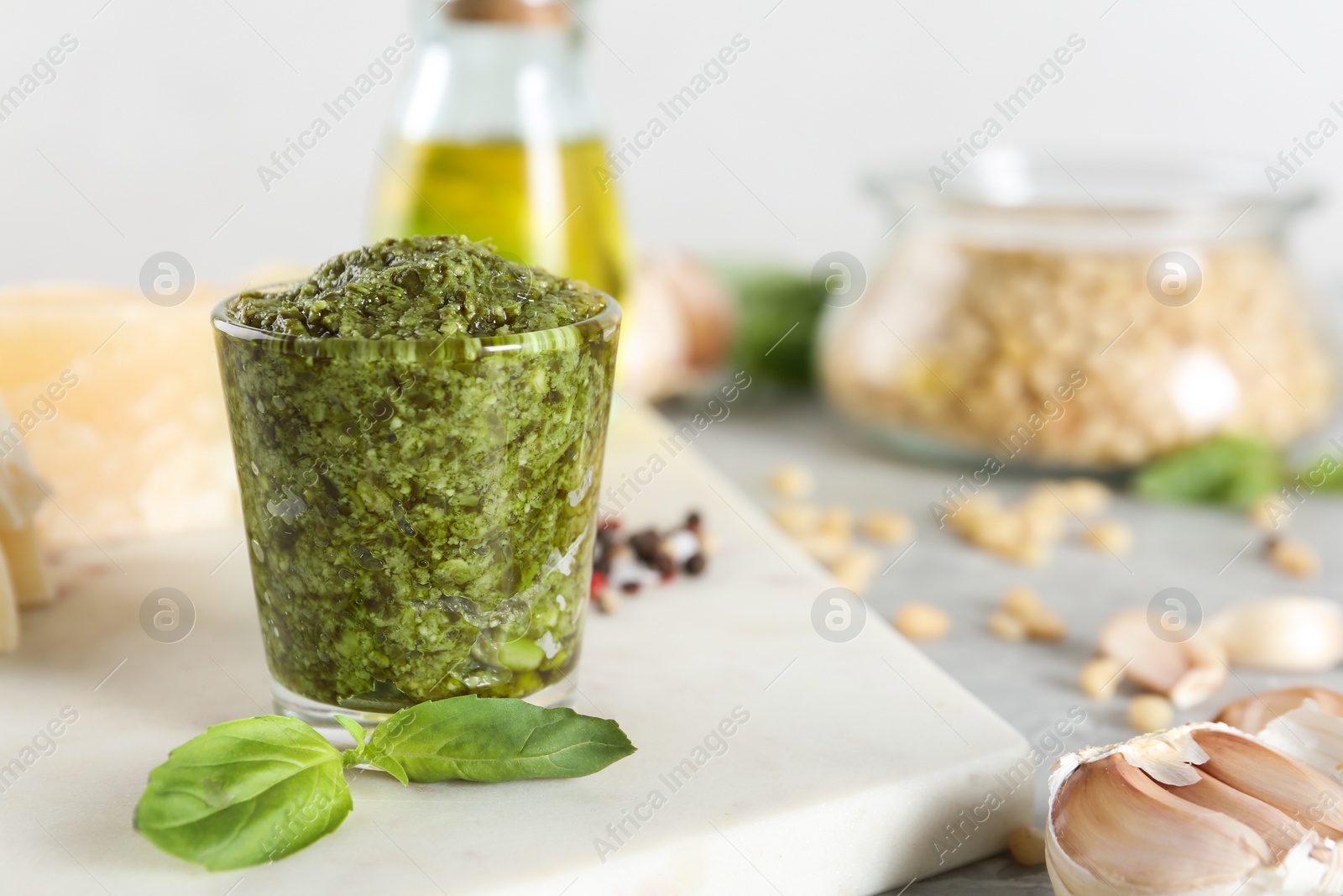 Photo of Board with glass of pesto sauce and basil on table. Space for text