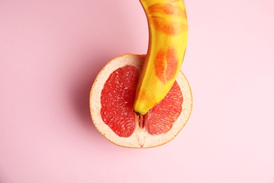 Photo of Flat lay composition with fresh banana  and grapefruit on pink background. Sex concept