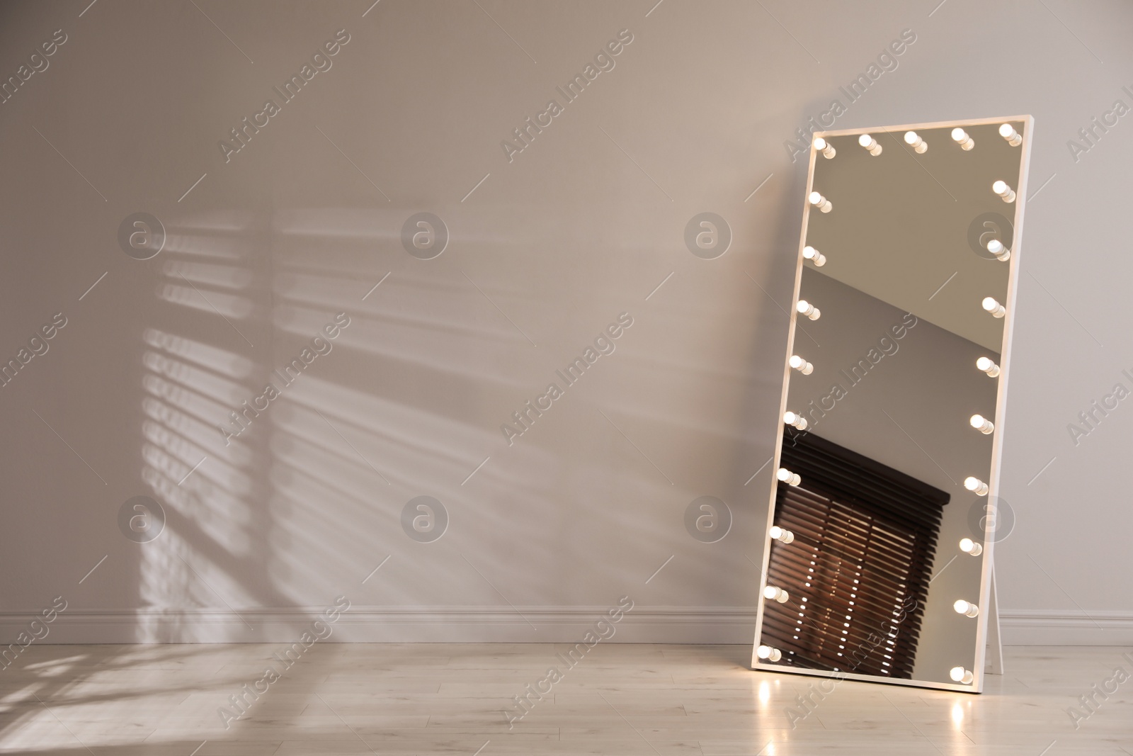 Photo of Stylish mirror with light bulbs near white wall indoors. Interior element