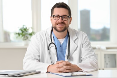Photo of Portrait of smiling doctor at table in clinic