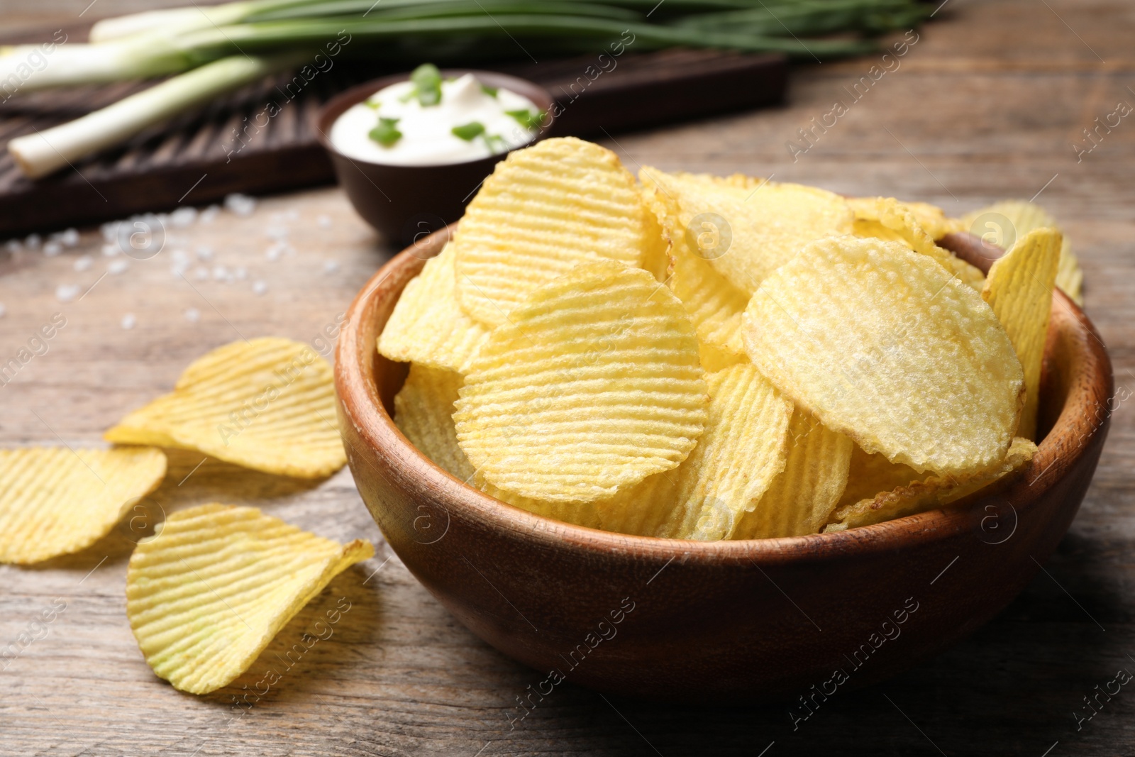 Photo of Delicious crispy potato chips in bowl on table, closeup with space for text