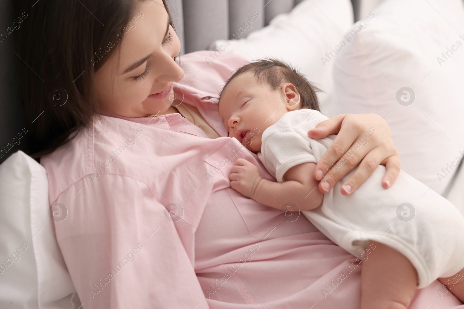 Photo of Mother with her sleeping newborn baby in bed