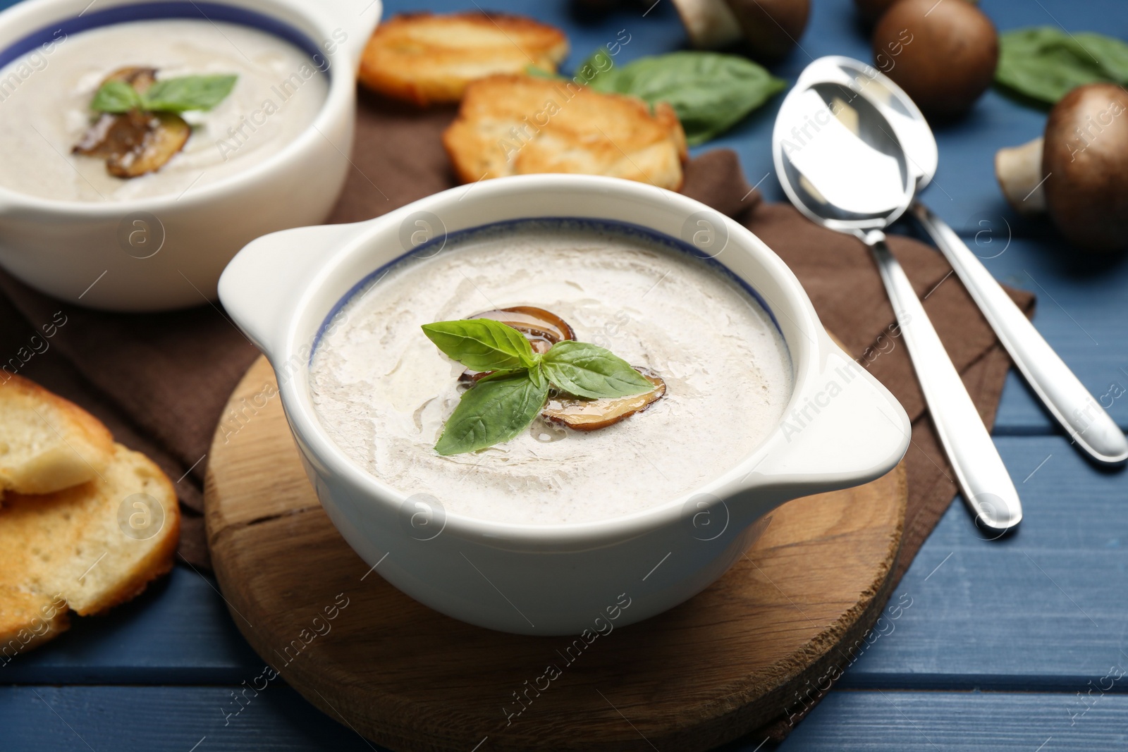 Photo of Fresh homemade mushroom soup served on blue wooden table