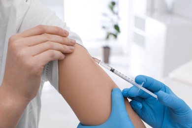 Photo of Doctor giving injection to woman in hospital, closeup. Immunization concept