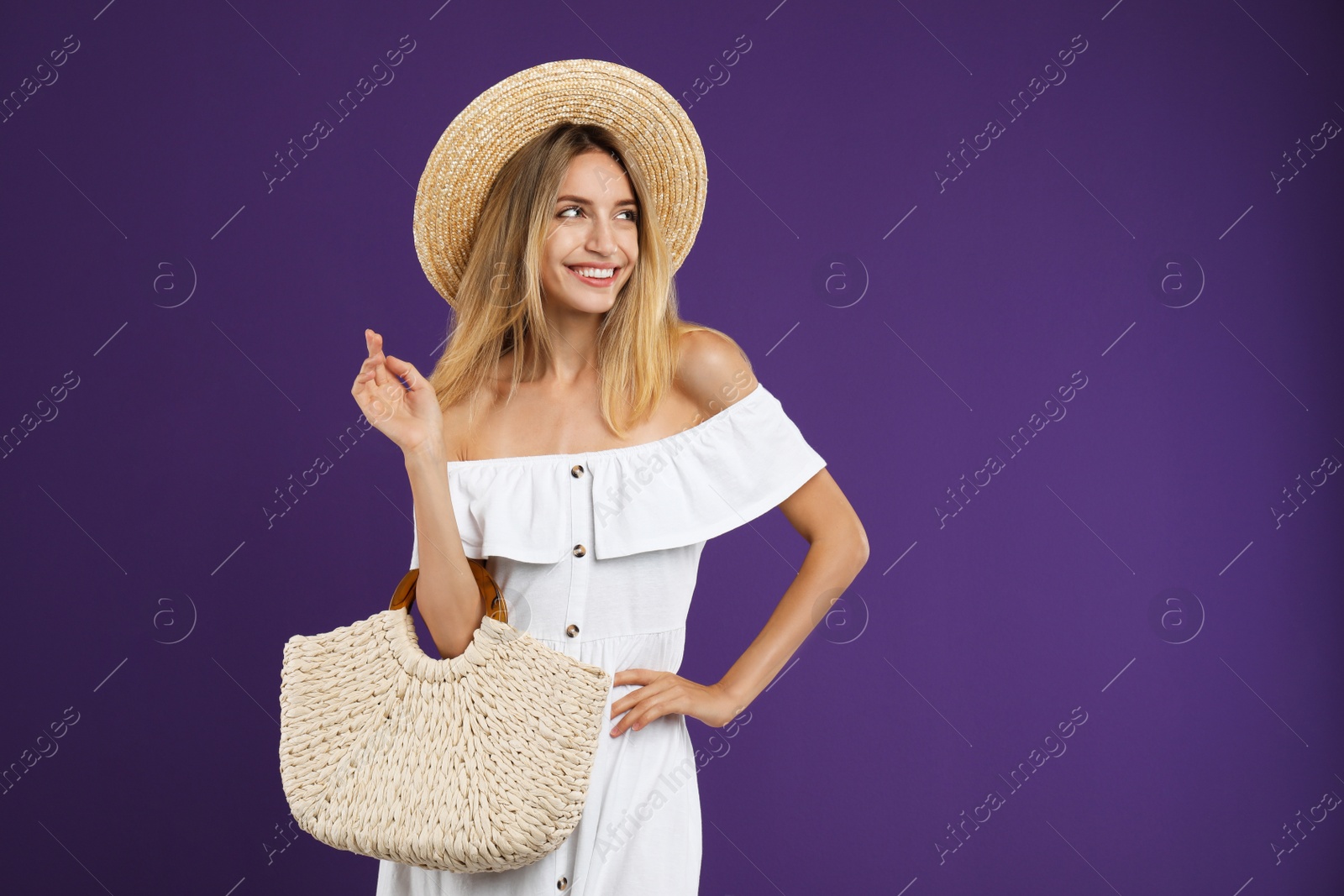 Photo of Beautiful young woman with stylish straw bag on purple background. Space for text