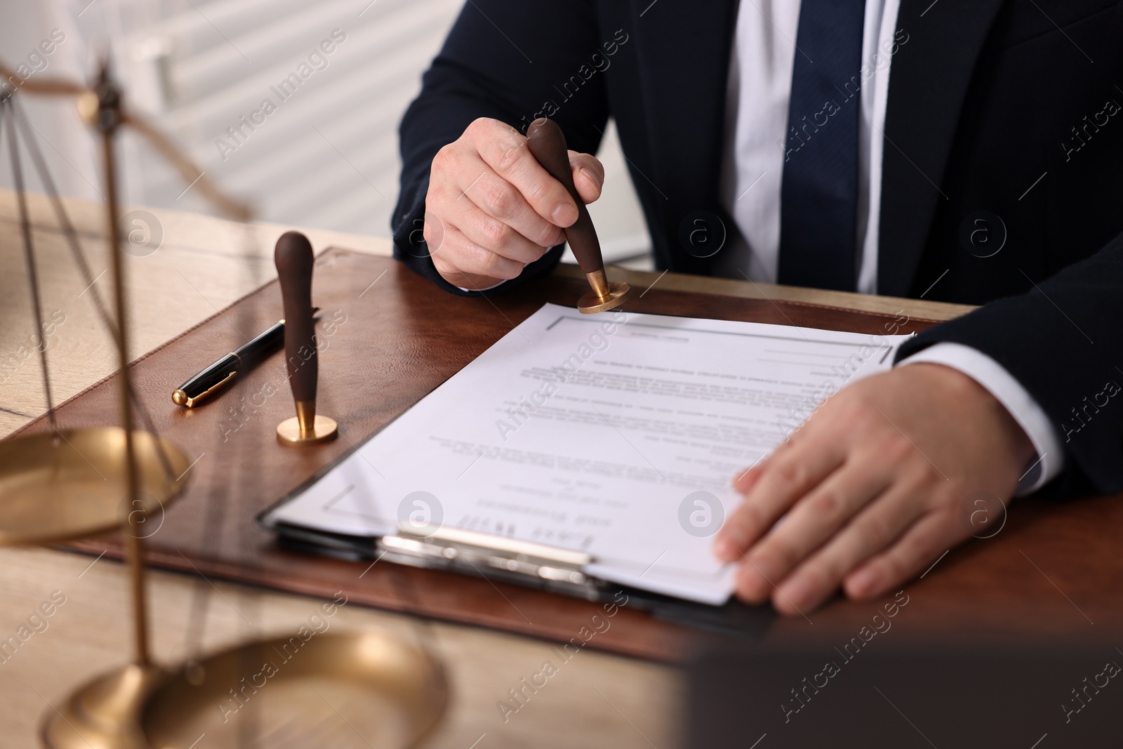 Photo of Notary stamping document at wooden table in office, closeup