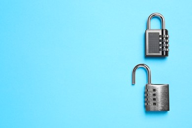Steel combination padlocks on light blue background, top view. Space for text