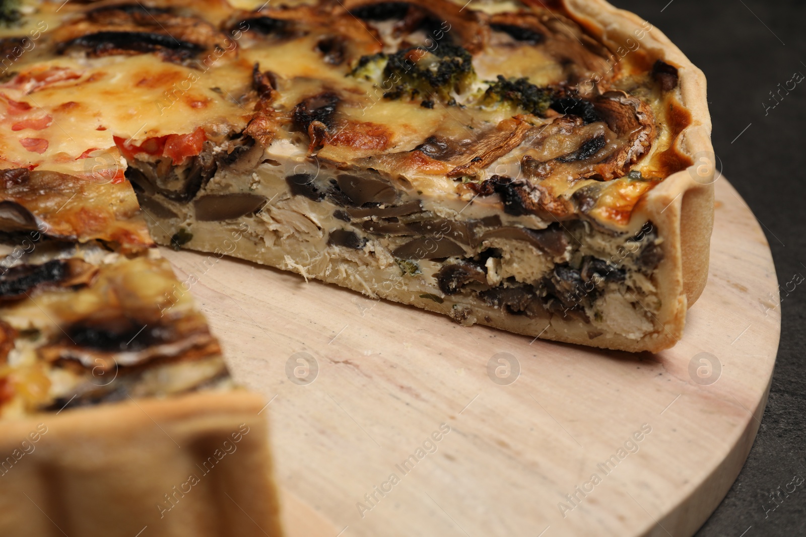 Photo of Delicious quiche with mushrooms on wooden board, closeup