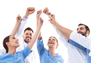 Photo of Team of medical doctors raising hands together on white background. Unity concept