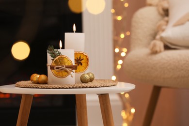 Beautiful candles decorated with dry orange slices and cinnamon sticks on white table indoors. Christmas atmosphere