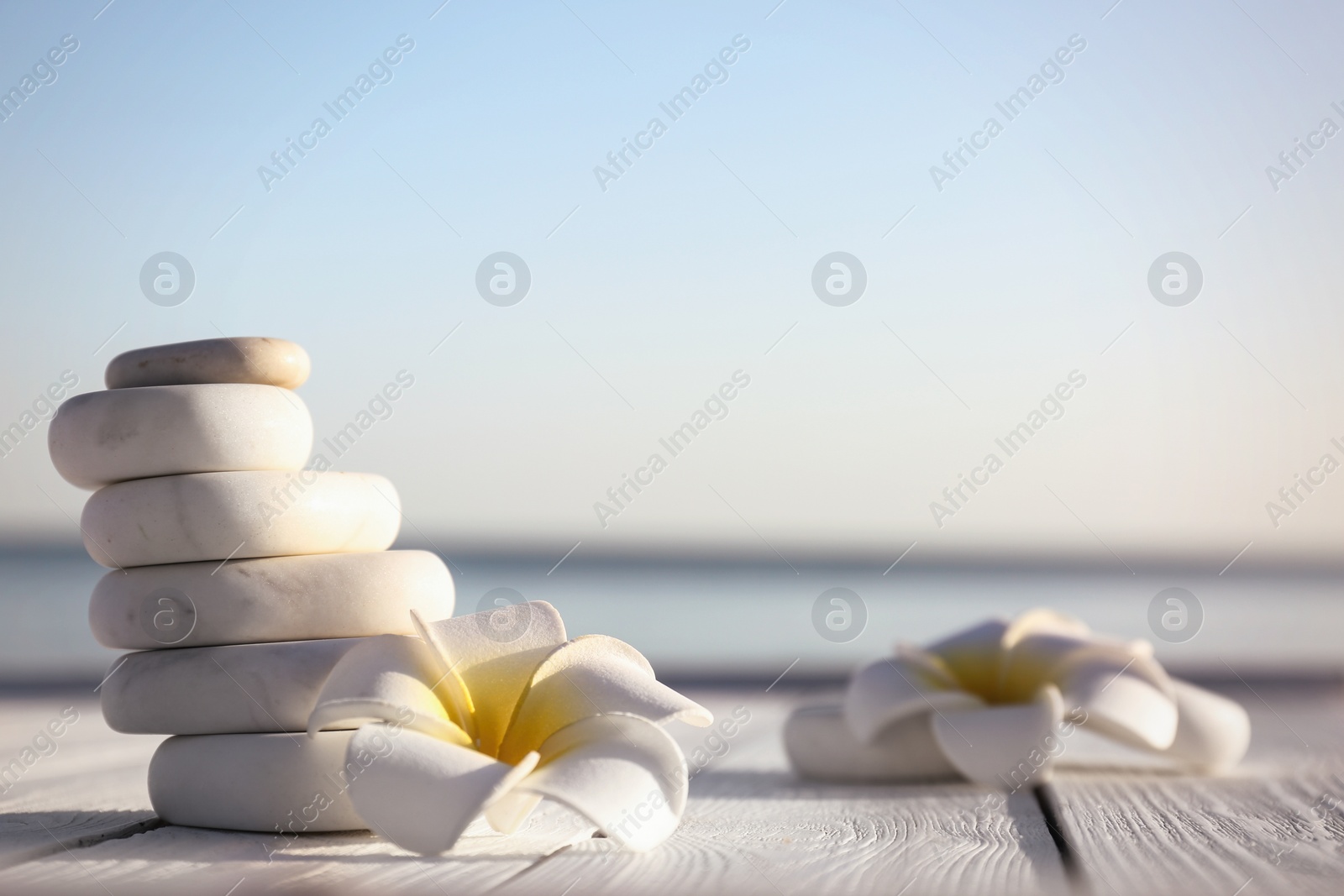 Photo of Stack of white marble stones and beautiful flower on wooden deck, space for text. Zen concept