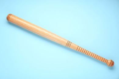 Photo of Wooden baseball bat on light blue background, top view. Sports equipment