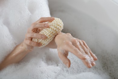 Woman rubbing her forearm with sponge while taking bath, closeup