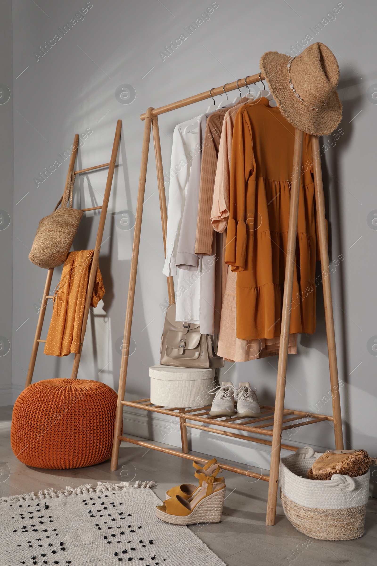 Photo of Modern dressing room interior with stylish clothes, shoes and orange pouf