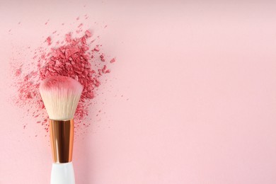 Photo of Makeup brush and scattered blush on pink background, top view. Space for text