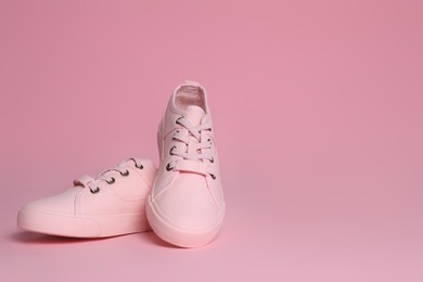 Pair of stylish canvas shoes on pink background. Space for text