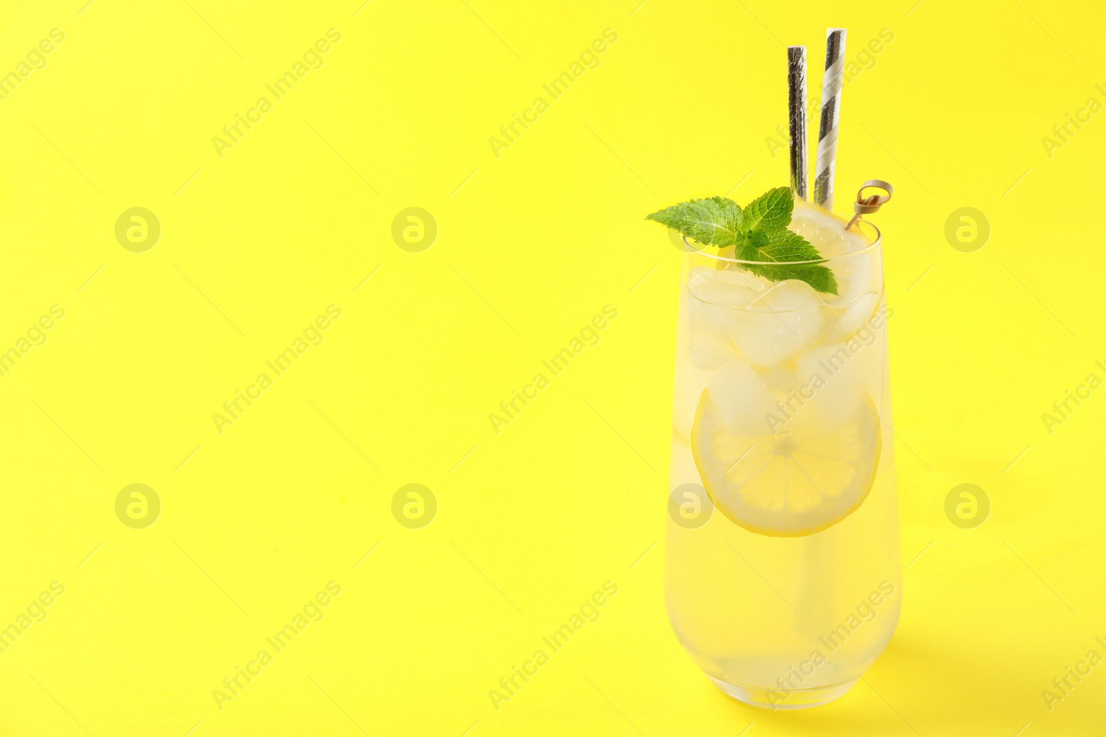 Photo of Natural lemonade on yellow background, space for text. Summer refreshing drink