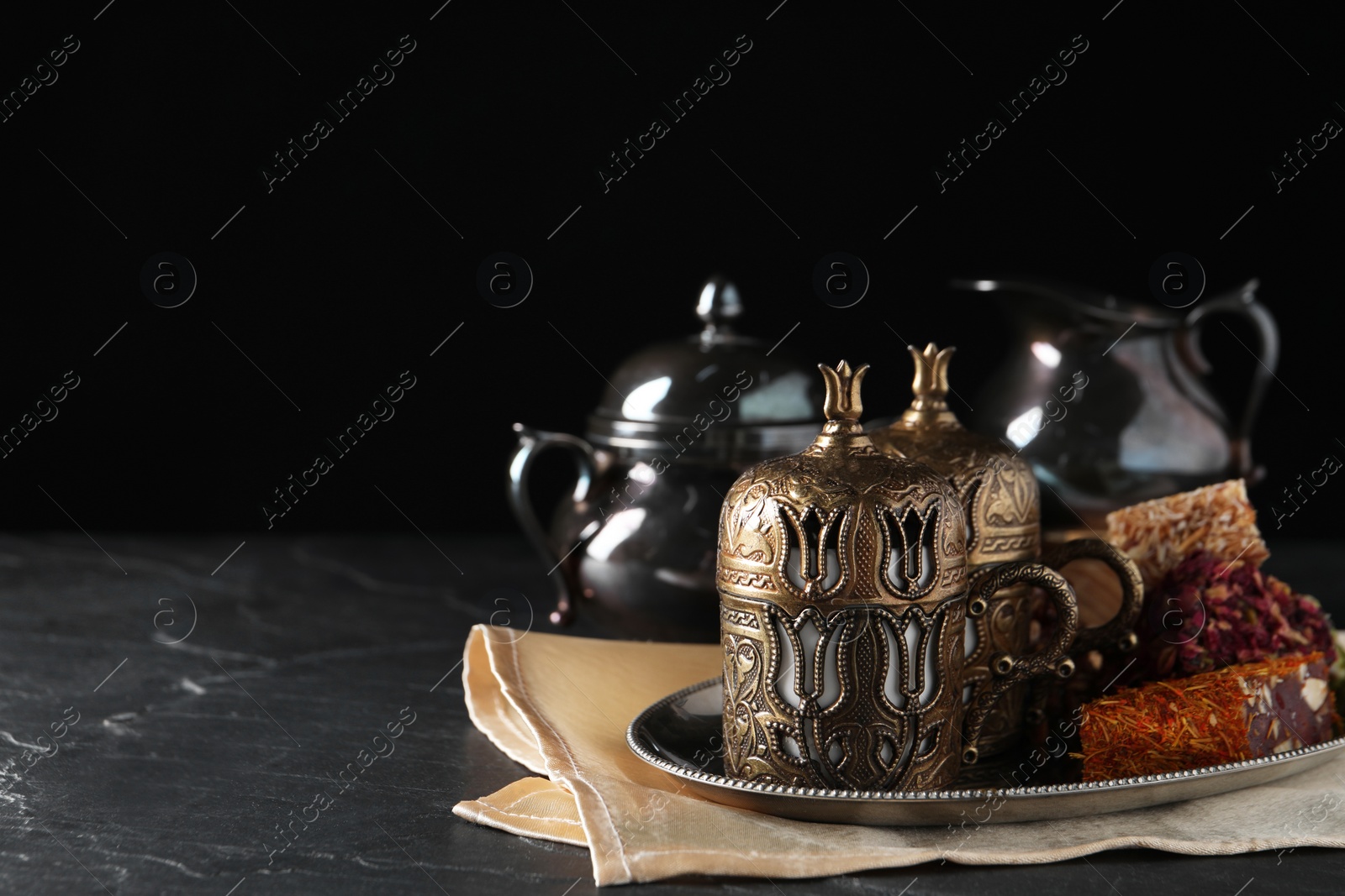 Photo of Tea and Turkish delight served in vintage tea set on dark grey textured table, space for text